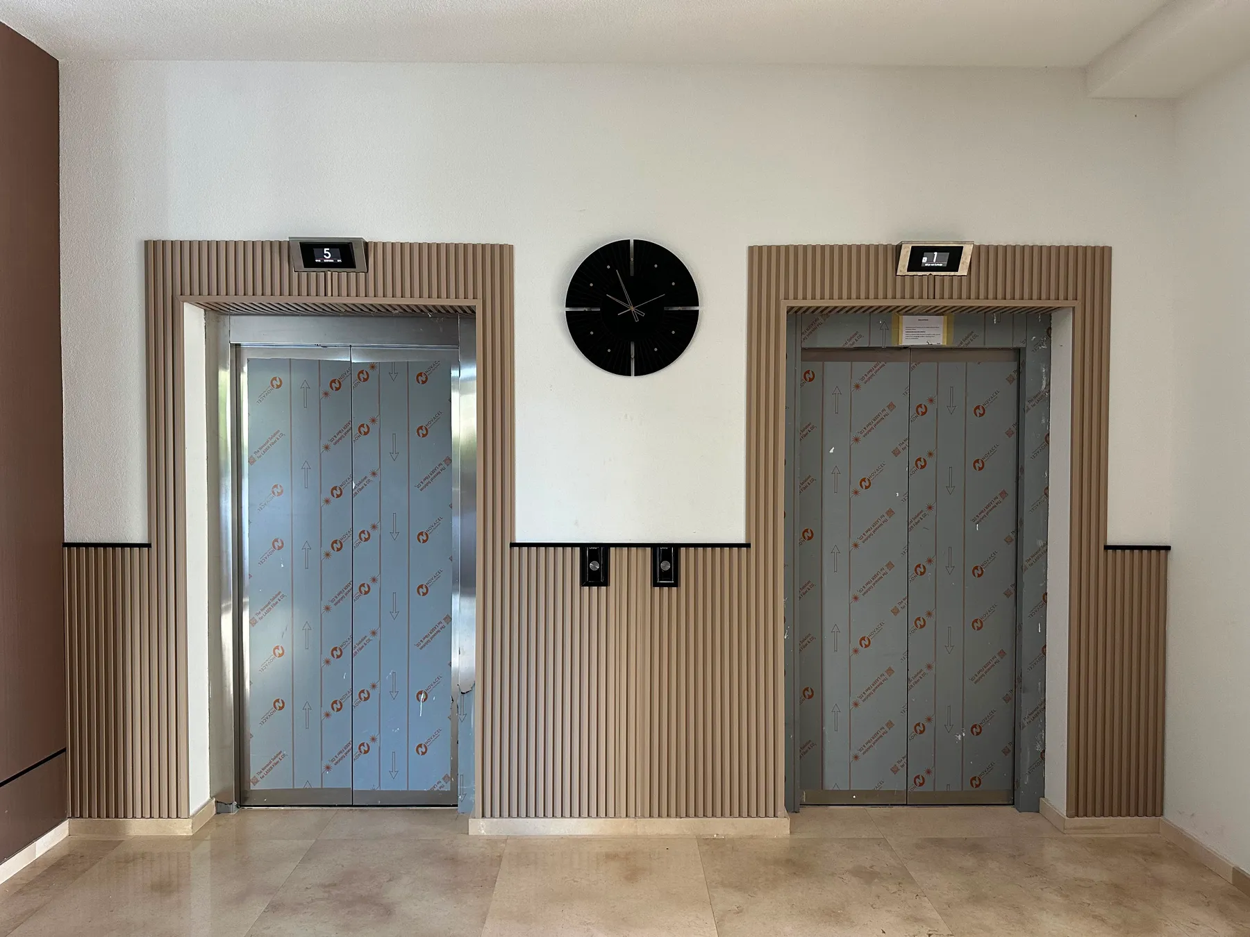 Isti ulazni prostor poslije — zid oko liftova obložen WPC prečkicama
